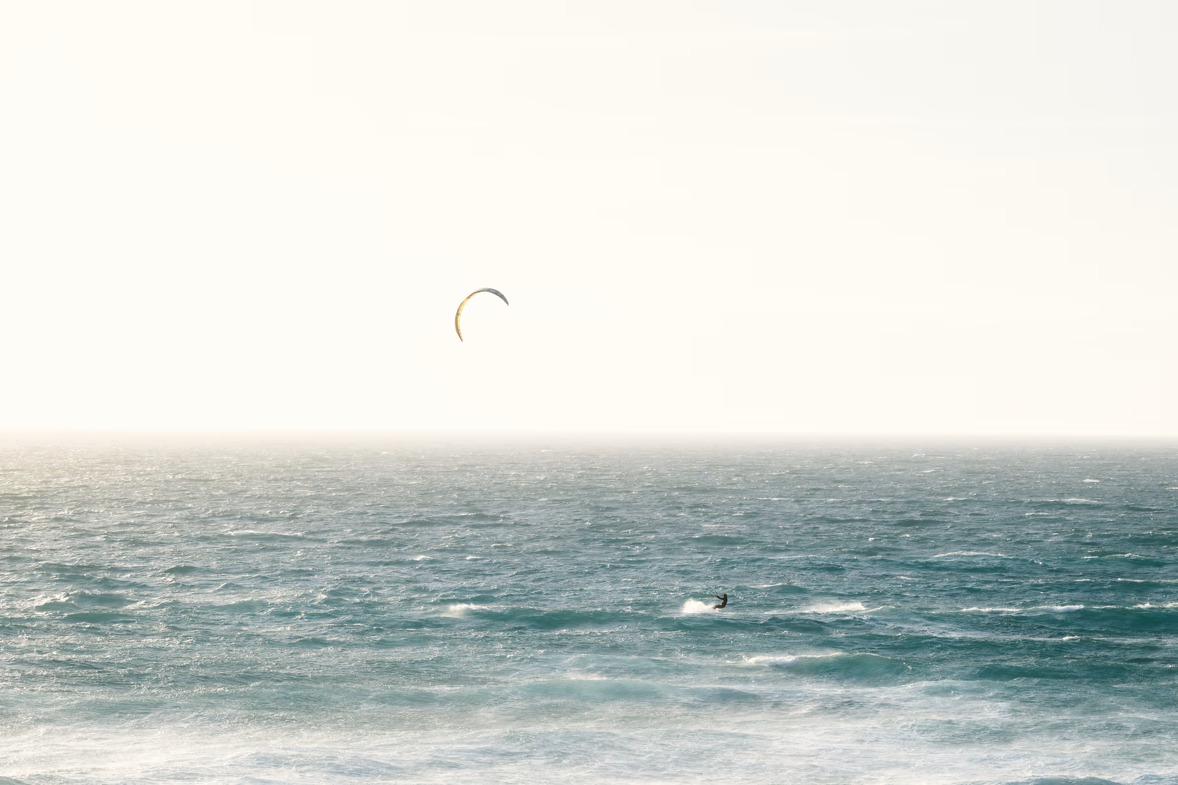 Lone kite surfer on a vast ocean